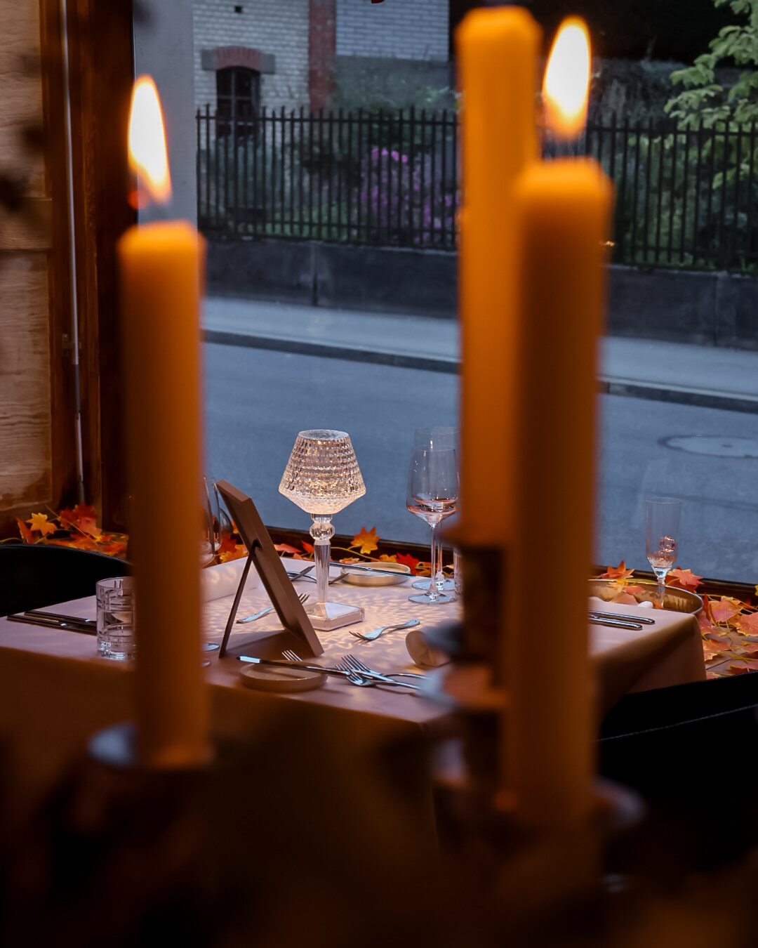 Kerzenlicht am Fenster vor gedecktem Tisch