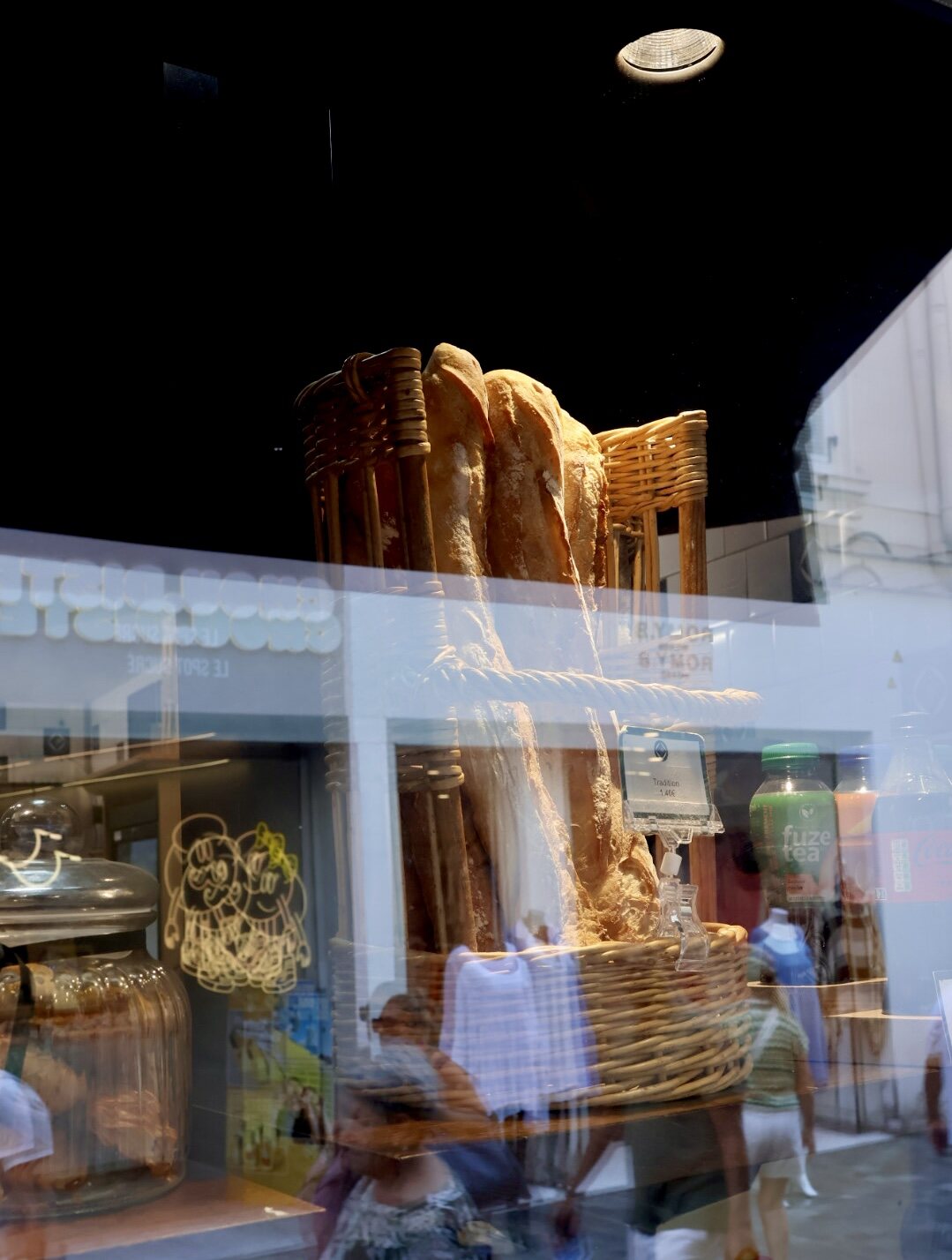 Baguettes im Korb hinter einer Scheibe, darin spiegelt sich die Strasse